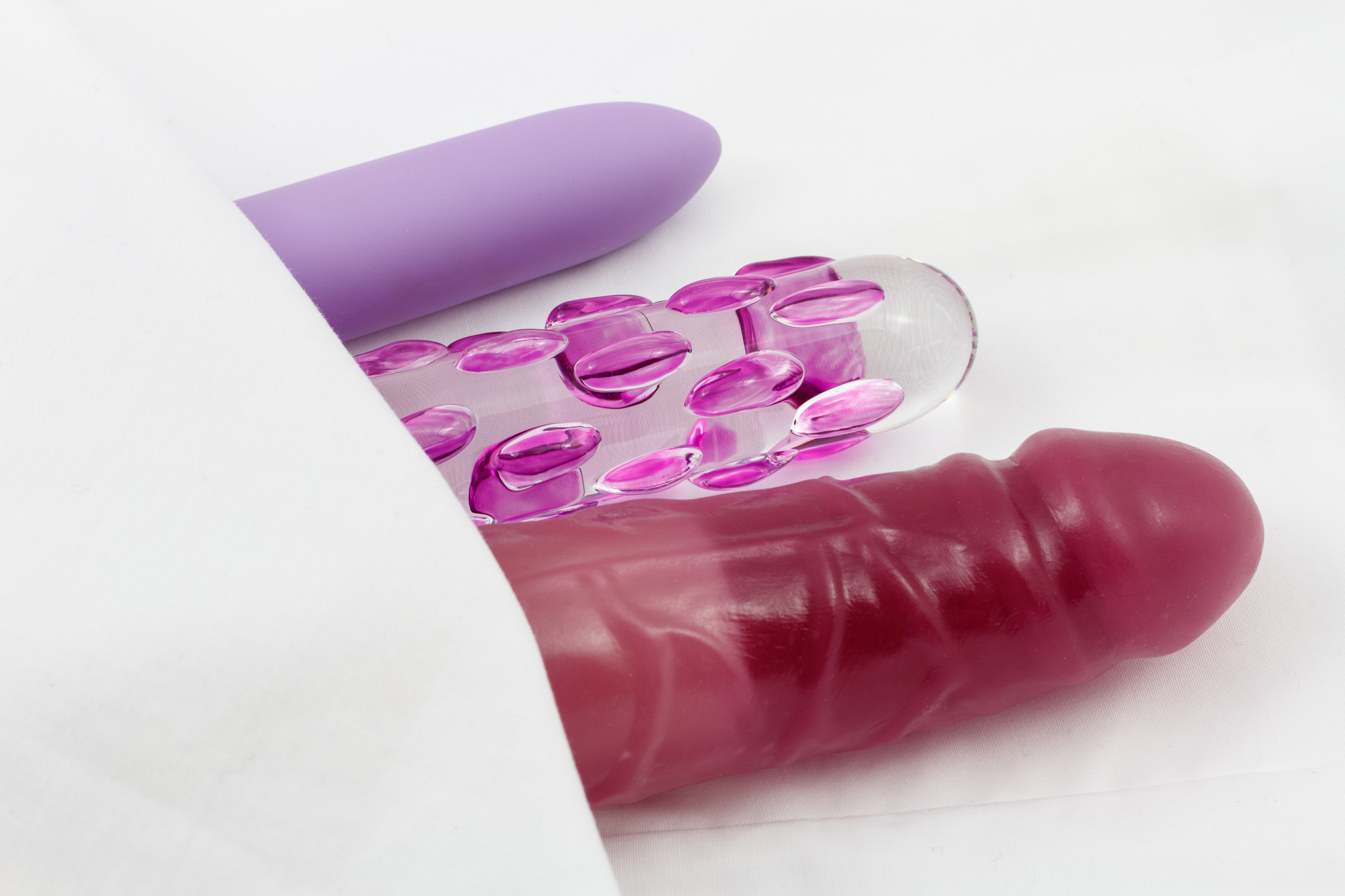 Sex Toys - Glass dildo and vibrators in bed